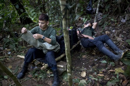Oscar, un soldado rebelde del frente 36 de las fuerzas armadas revolucionarias de Colombia, FARC, repara un par de pantalones al mismo tiempo su "socia" Gisell descansa en una hamaca, en un campo oculto en el estado de Antioquia, en los Andes del noroeste de Colombia.