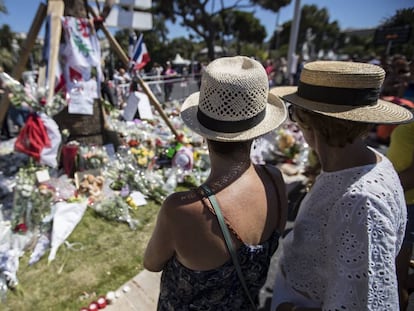 Varios turistas, ante los ramos de flores colocados en el lugar del atentado de Niza. 