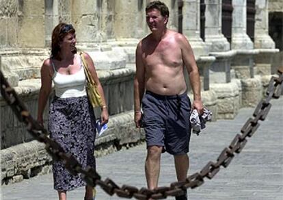 Una pareja de turistas pasea por Sevilla bajo un sol abrasador.