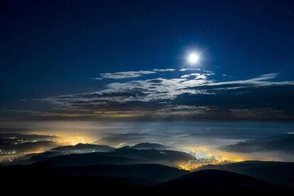 La luna brilla por encima del manto de nubes que se cierne sobre un paraje montañoso cercano a Salgotarjan, a unos 100 km al noreste de Budapest.