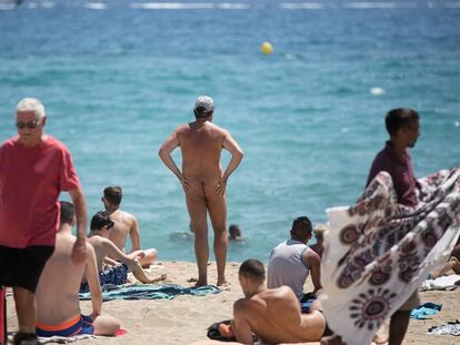 Un nudista a la platja de la Mar Bella envoltat de persones amb banyador.
