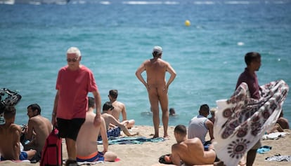 Un nudista a la platja de la Mar Bella envoltat de persones amb banyador.