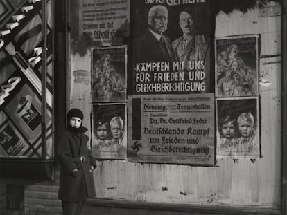 Mara, hija de Vishniac, posa delante de un cartel electoral de Hindenburg y Hitler que lee: "El mariscal y el cabo: lucha con nosotros por la paz y la igualdad de derechos,"Wilmersdorf, Berlín, 1933