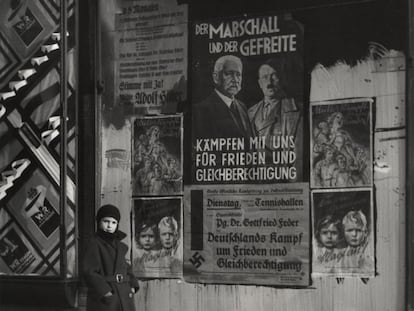 Mara, hija de Vishniac, posa delante de un cartel electoral de Hindenburg y Hitler que lee: "El mariscal y el cabo: lucha con nosotros por la paz y la igualdad de derechos,"Wilmersdorf, Berlín, 1933