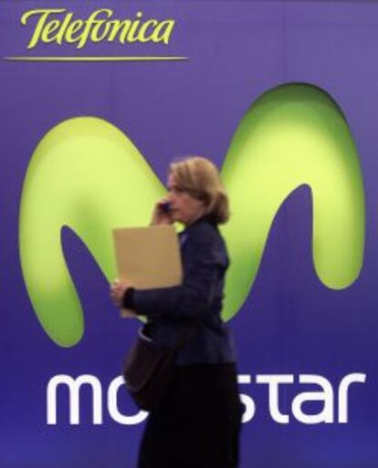 Una mujer habla por telefono junto a un cartel de Movistar. 