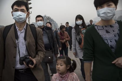 Varias personas caminan con mascarilla por la plaza de Tiananmen de Pekín, en un día de contaminación.