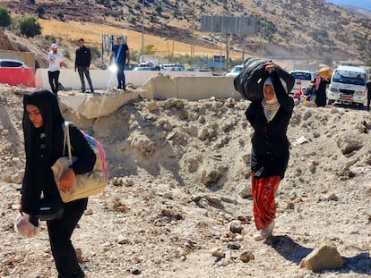 Civiles caminan junto a un cráter de proyectil lanzado por israel en el cruce fronterizo de Masnaa, el principal puesto fronterizo con Siria.