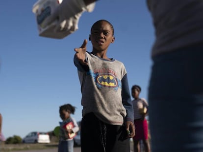 Un niño residente en el asentamiento informal de  Masincedane, en Ciudad del Cabo (Sudáfrica) recibe una ración de comida de parte de una organización benéfica el pasado 28 de abril de 2020. 