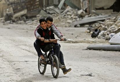 Dos jóvenes sirios montan en bicicleta entre los restos del barrio de Shaar, al norte de Alepo (Siria).