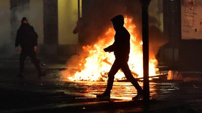 Varios encapuchados junto a un fuego, en una protesta contra las medidas anticovid, este lunes en Turín.