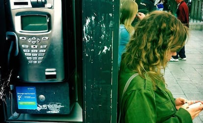 Una chica apoyada a una cabina telefónica en Madrid.