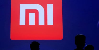 Varias personas pasan delante de un logo de Xiaomi.