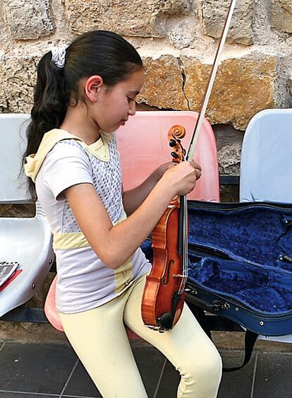 Una alumna de la escuela prepara su violín.