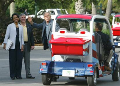 Bush saluda desde uno de los pequeños vehículos en los que han llegado los líderes.