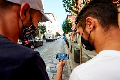 Dos personas miran la pantalla de su teléfono móvil.