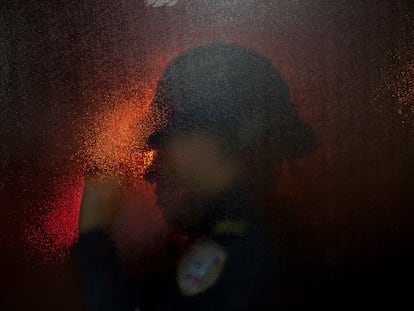 La silueta de una policía a través de la puerta de una sala de emergencias en un hospital de San Pedro Sula (Honduras).