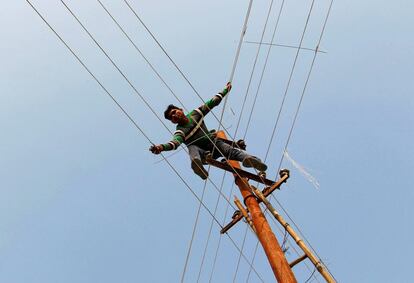 Un hombre instala cables eléctricos para el festival Magh Mela, en Allahabad (India).