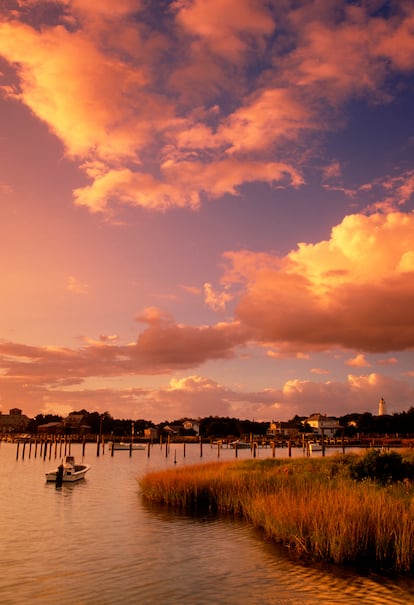Una de piratas. Ocrakoke (Carolina del Norte, EE UU). La historia de Ocracoke suena casi como un cuento de hadas. Barbanegra y otros piratas solían esconderse en calas alrededor de esta isla larga y esbelta frente a la costa de Carolina del Norte, esperando para emboscar barcos desprevenidos. Los ponis salvajes traídos por exploradores náufragos en el siglo XVII compartieron espacio con los forajidos, y sus descendientes aún pastan en medio de algunas de las mejores vistas de la isla. Mientras tanto, los isleños de Ocracoke desarrollaron un acento único que se mantiene fiel a sus raíces como dialecto británico del siglo XVII. Hoy en día, no es difícil sumergirse en el original pasado de la isla. Por ejemplo, viendo a los ponis descendientes de los originales que viven cerca de la playa, viendo objetos piratas en un museo o escuchando el acento de los ancianos Hoi Toiders (llamados así por la pronunciación de los isleños de "marea alta") hablado en la calle. Pero en Ocracoke también se puede ir a una de las playas más bonitas de Estados Unidos, contemplar delfines o recorrer las costas en kayak al atardecer.
Imprescindible ir al Faro de Ocracoke, uno de sus rincones más fotogénicos o acercarse al Coyote Music Den, en la típica casa de tablones de madera, junto al agua, un pequeño lugar dirigido por músicos con una buena programación r de folk, rock, blues y jazz.