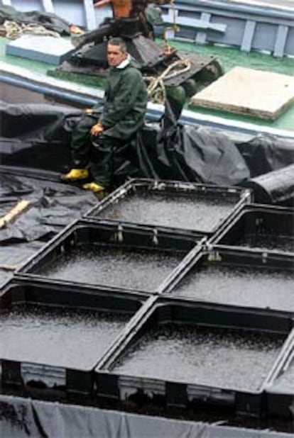 Un pescador descansaba ayer tras recoger del mar toneladas de fuel y almacenarlas en contenedores.