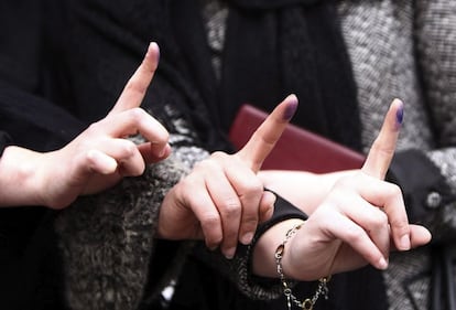 Mujeres iraníes muestran sus dedos manchados de tinta tras votar en las elecciones legislativas.