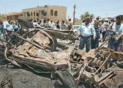 Agentes de policía contemplan el coche bomba que ha explotado al noroeste de Bagdad.