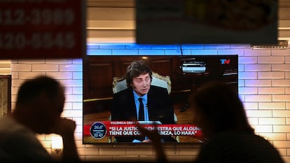 Dos personas siguen en la televisión de un restaurante la entrevista al presidente de Argentina, Javier Milei, este lunes en Buenos Aires.