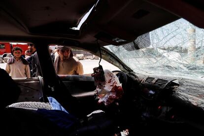 Varios afganos inspeccionan el coche de un civil dañado por la explosión de una bomba en Kabul (Afganistán), el 31 de mayo de 2019. Al menos 5 personas murieron y otras 7 resultaron heridas, entre ellas cuatro soldados de la OTAN, en un ataque suicida con coche bomba perpetrado este viernes contra un convoy de las fuerzas internacionales en Kabul.