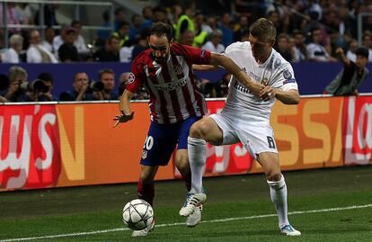 Juanfran (i) del Atlético de Madrid y Toni Kroos del Real Madrid intentan conseguir la pelota.