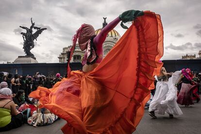 Mujeres del colectivo 'Capuchas Rosas' acompañan la marcha con música y baile, aquí retratadas frente al Palacio de Bellas Artes, en Ciudad de México, resguardado con vallas colocadas la noche anterior.