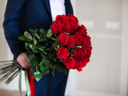 Un hombre sujeta un ramo de rosas.