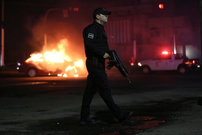 Police officers stand at a scene where a vehicle has been set alight by members of the Jalisco New Generation Cartel (CJNG) following the detention of one of its leaders by Mexican federal forces, in Zapopan, in Jalisco state, Mexico August 9, 2022. REUTERS/Fernando Carranza
