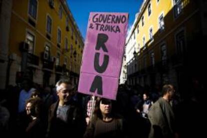 Un manifestante sostiene una pancarta con las palabras "el gobierno y la troika fuera" en la manifestación contra las políticas de austeridad del gobierno, en el centro de Lisboa, Portugal.