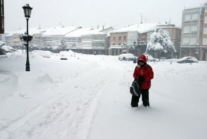 Un peaton camina por una calle cubierta de nieve en Aguilar de Campoo, Palencia.