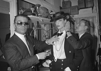 El diseñador de moda alemán Karl Lagerfeld (a la izquierda) y el estilista Alexandre ajustan el atuendo de una modelo durante su primera colección primavera-verano de Chanel, en 1983.