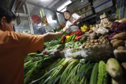 Una vendedora de vegetales atiende a un cliente en un mercado de Pekín (China). EFE/Archivo