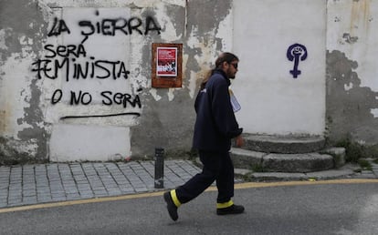 Un cartero pasa por delante de una pintada en Bustarviejo, este jueves