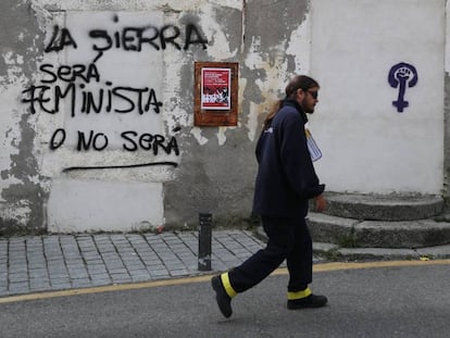 Un cartero pasa por delante de una pintada en Bustarviejo, este jueves