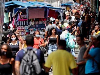 Jovem sem máscara caminha em uma movimentada rua comercial em São Paulo, no momento em que o Brasil vive uma aceleração da pandemia.