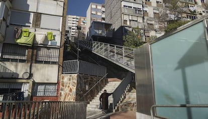 Una vecina sube por una escalera en la calle Calle Rasos de Peguera, en el barrio Ciutat Meridiana, en Barcelona.