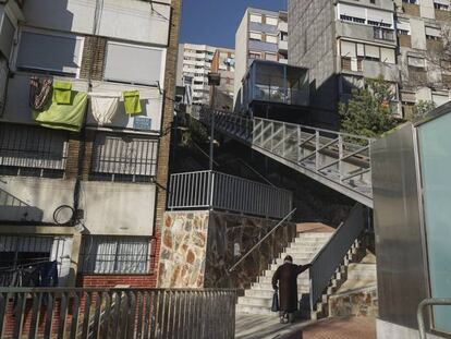 Una vecina sube por una escalera en la calle Calle Rasos de Peguera, en el barrio Ciutat Meridiana, en Barcelona.