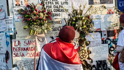 Un hombre con una bandera peruana frente a un homenaje a los dos jóvenes que murieron en las protestas en Perú.
