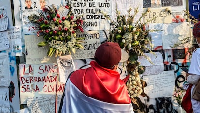 Un hombre con una bandera peruana frente a un homenaje a los dos jóvenes que murieron en las protestas en Perú.