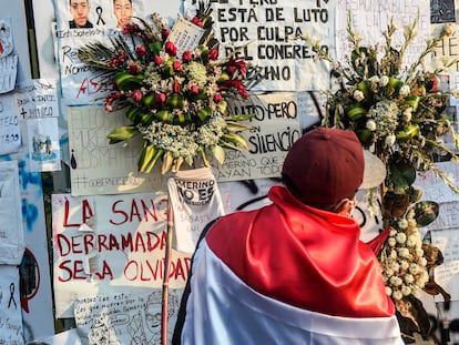 Un hombre con una bandera peruana frente a un homenaje a los dos jóvenes que murieron en las protestas en Perú.