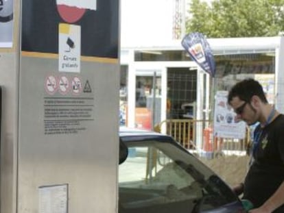 Un joven pone gasolina a su coche en un surtidor.