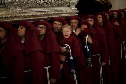 Dos gemelos son llevados por su padre y su tío, costaleros, en la procesión de La Salud en Málaga, el 29 de marzo de 2015.