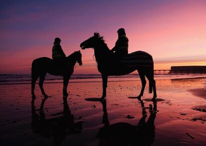 Dos jinetes se detienen a ver el amanecer en la playa de Saltburn-by-the-Sea (Inglaterra).
