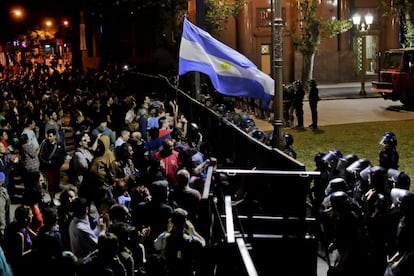 Los manifestantes ondean una bandera argentina frente a la valla del Congreso durante las protestas por la reforma del sistema de pensiones, el 19 de diciembre.
