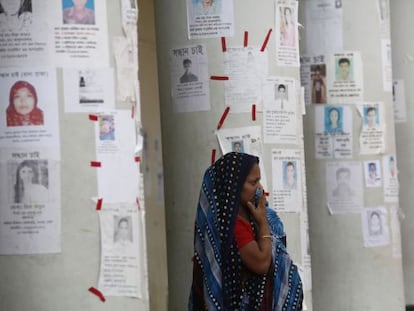 Una mujer espera noticias rodeada de carteles de desaparecidos.