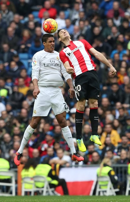 Varane (i) del Real Madrid y Aduriz (d) del Athletic de Bilbao golpean de cabeza.