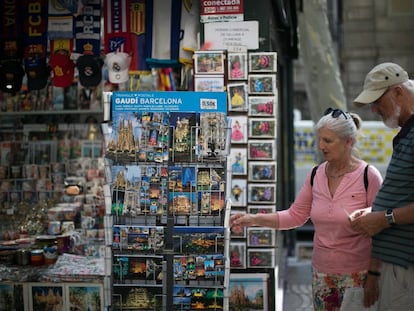 Dos turistas miran postales en un quiosco de la Rambla.